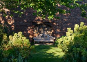 A wooden bench against the tudor bick wall in the Norfolk Garden